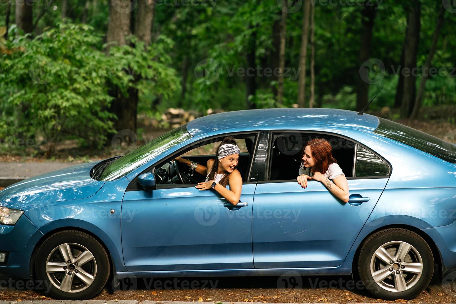 Two girlfriends fool around and laughing together in a car photo