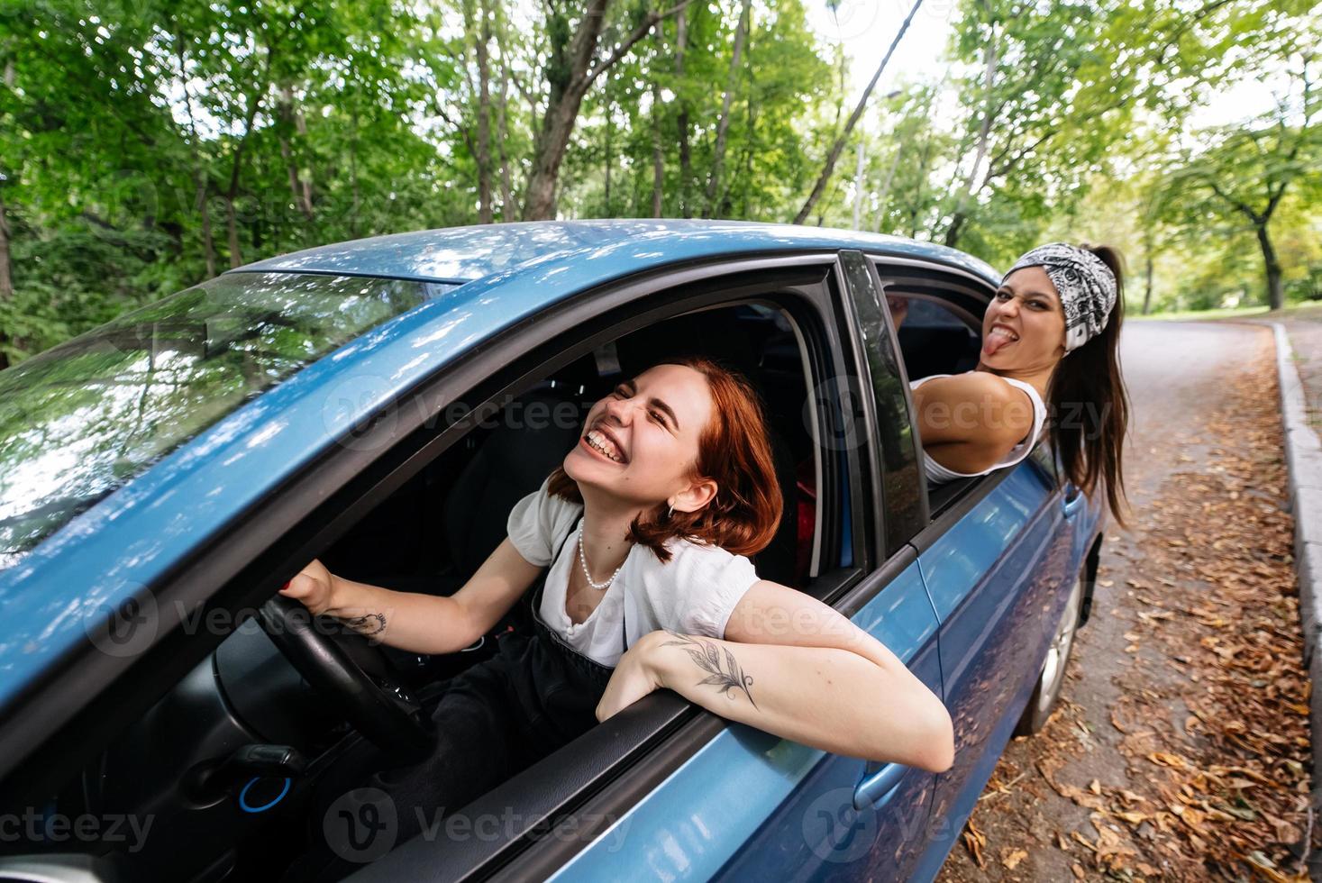 Two girlfriends fool around and laughing together in a car photo