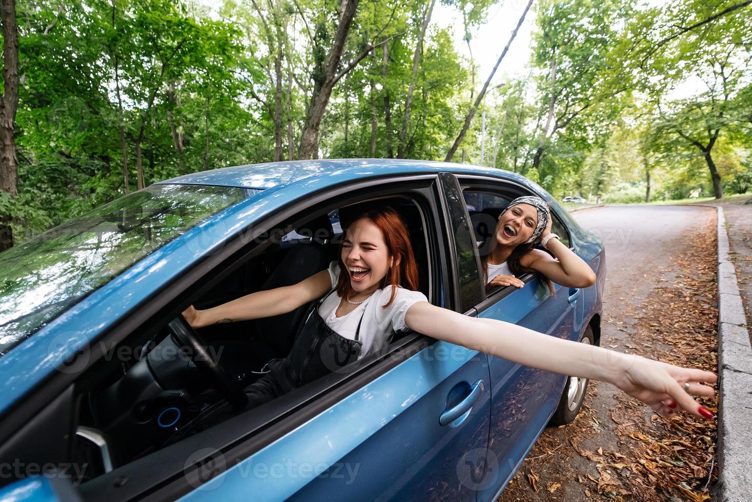 Two girlfriends fool around and laughing together in a car photo