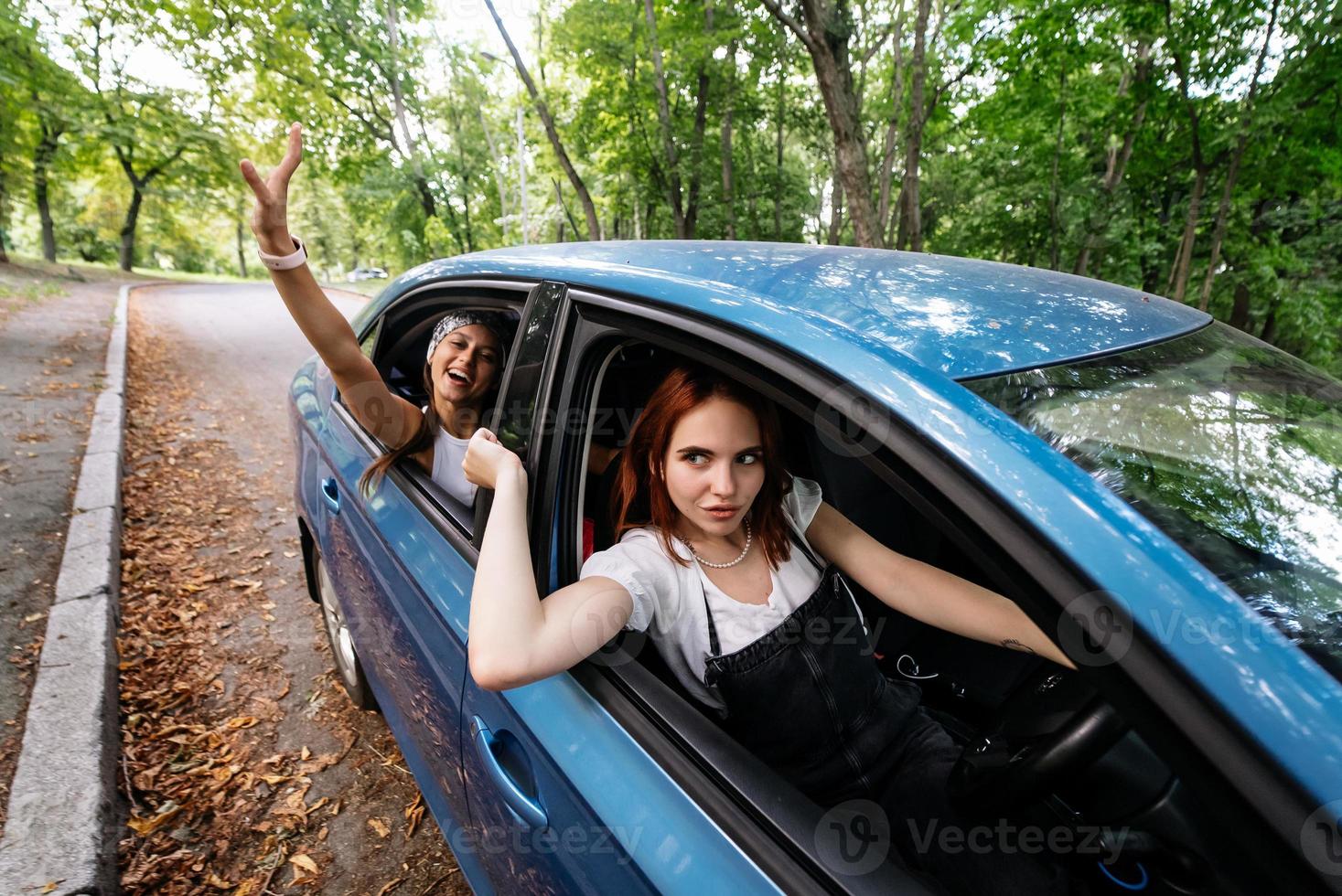 Two girlfriends fool around and laughing together in a car photo