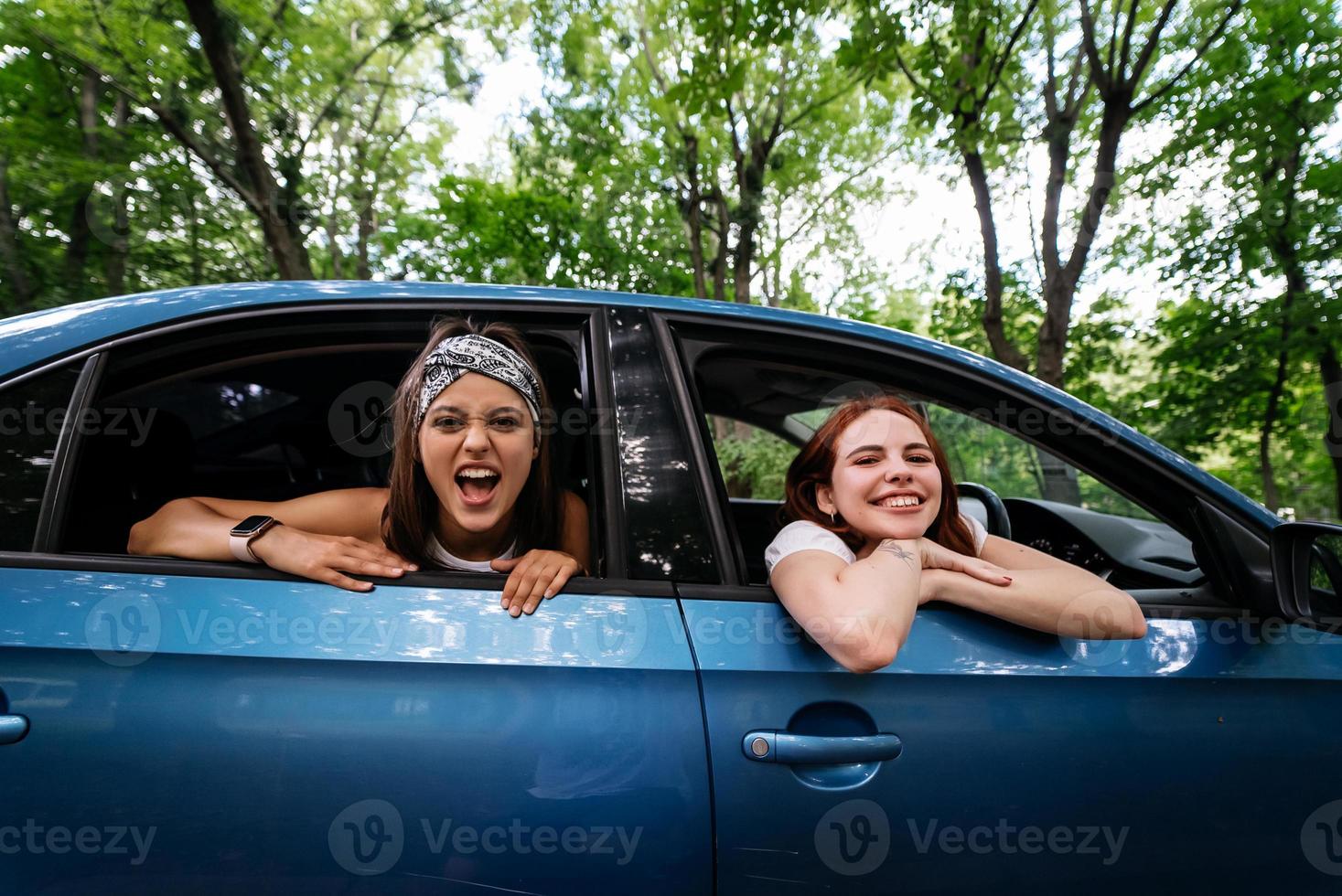 Two girlfriends fool around and laughing together in a car photo