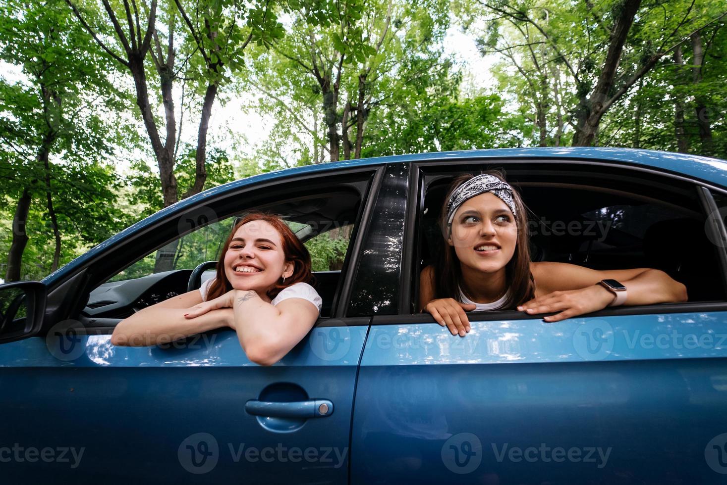 Two girlfriends fool around and laughing together in a car photo