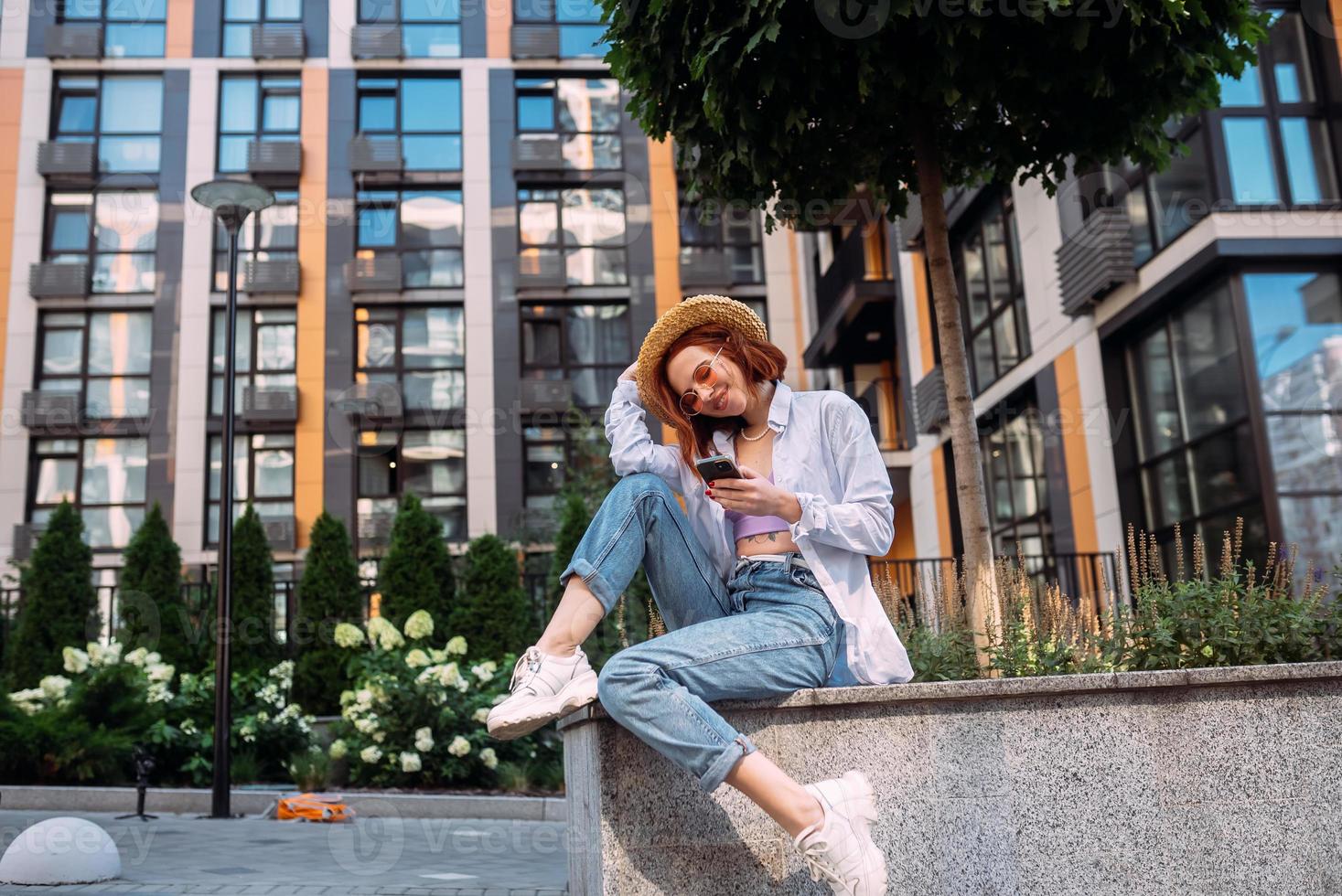 Young lady sitting stairs typing device outside urban city street photo