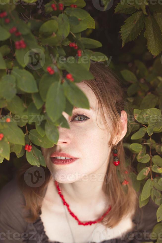 Close up woman peeking through winterberry leaves portrait picture photo