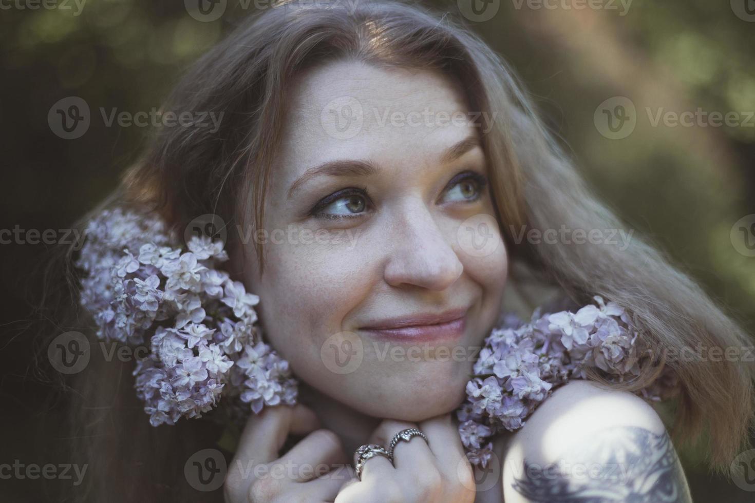 cerrar mujer feliz presionando tallos de lila para hacer frente a la imagen de retrato foto