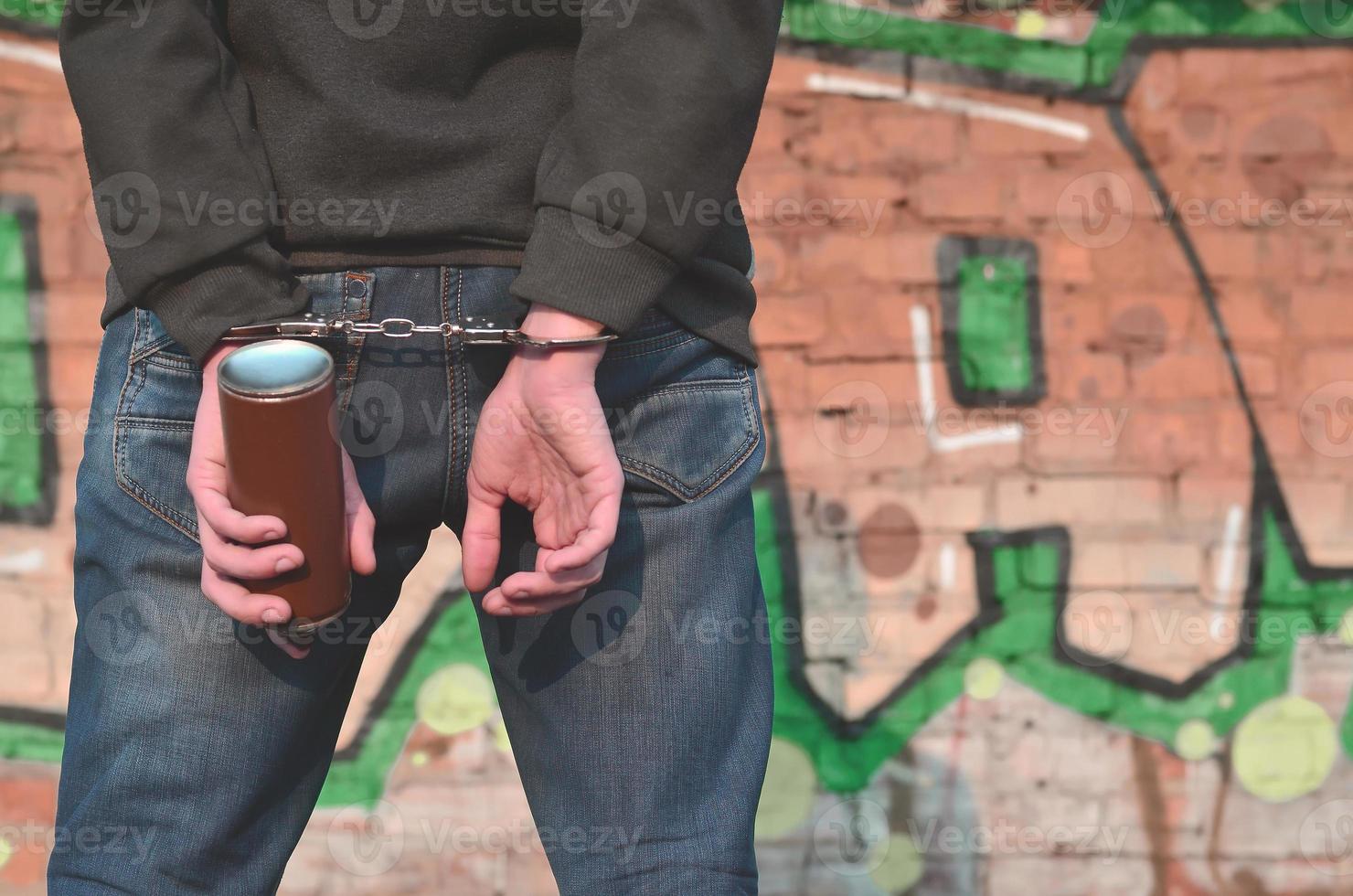 Young hoodlum caught by the police and shackled in handcuffs wit photo