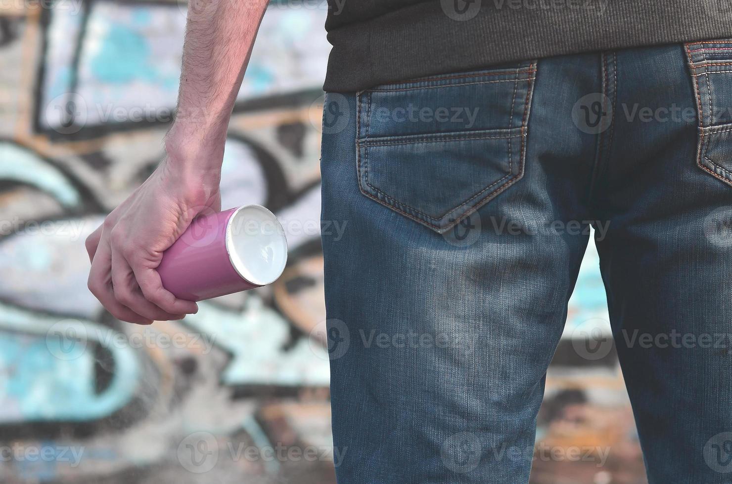 Rear view of a guy drawing a wall with aerosol paint photo