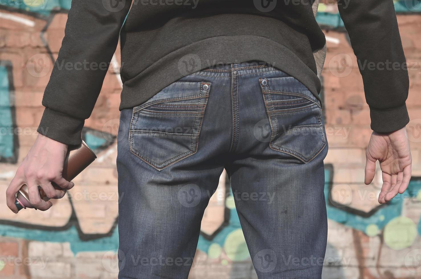 Rear view of a guy drawing a wall with aerosol paint photo
