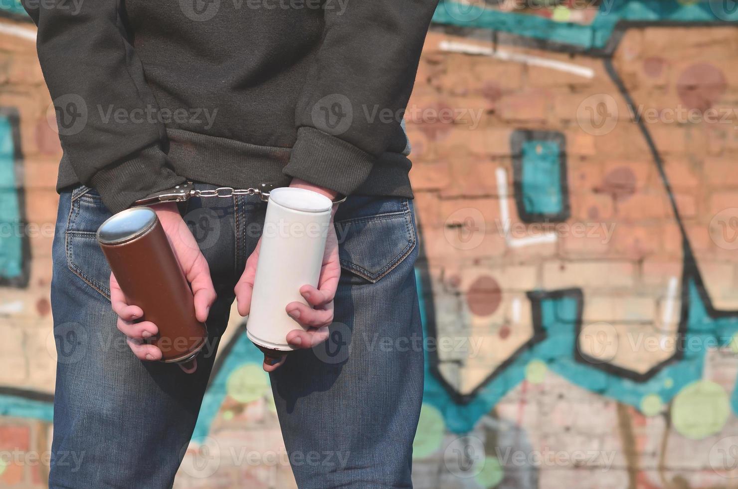 A rear view of an arrested street artist in handcuffs with aeros photo