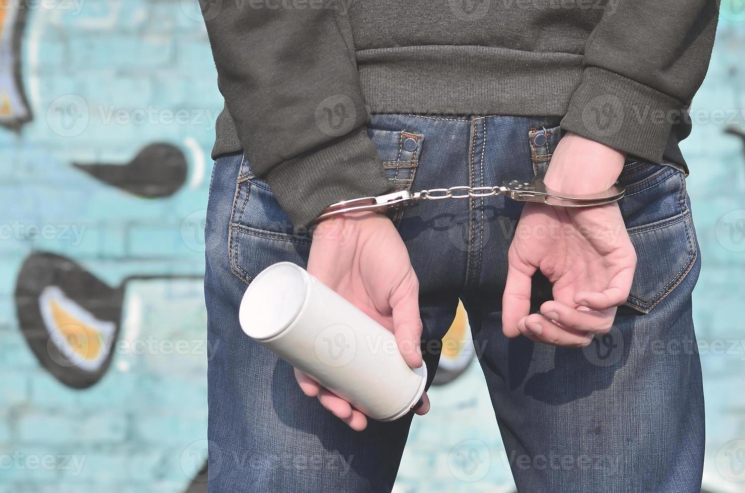 Young hoodlum caught by the police and shackled in handcuffs wit photo