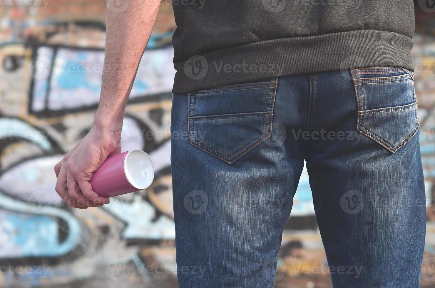 Graffiti artist with a spray can in his hand. Back view photo