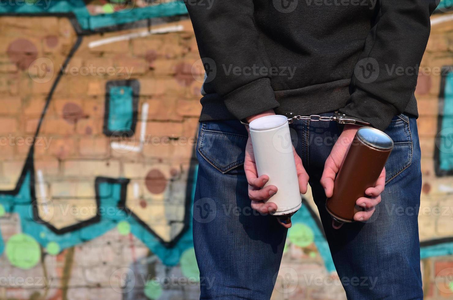 A rear view of an arrested street artist in handcuffs with aeros photo