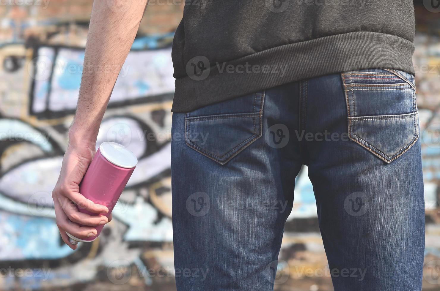 Graffiti artist with a spray can in his hand. Back view photo