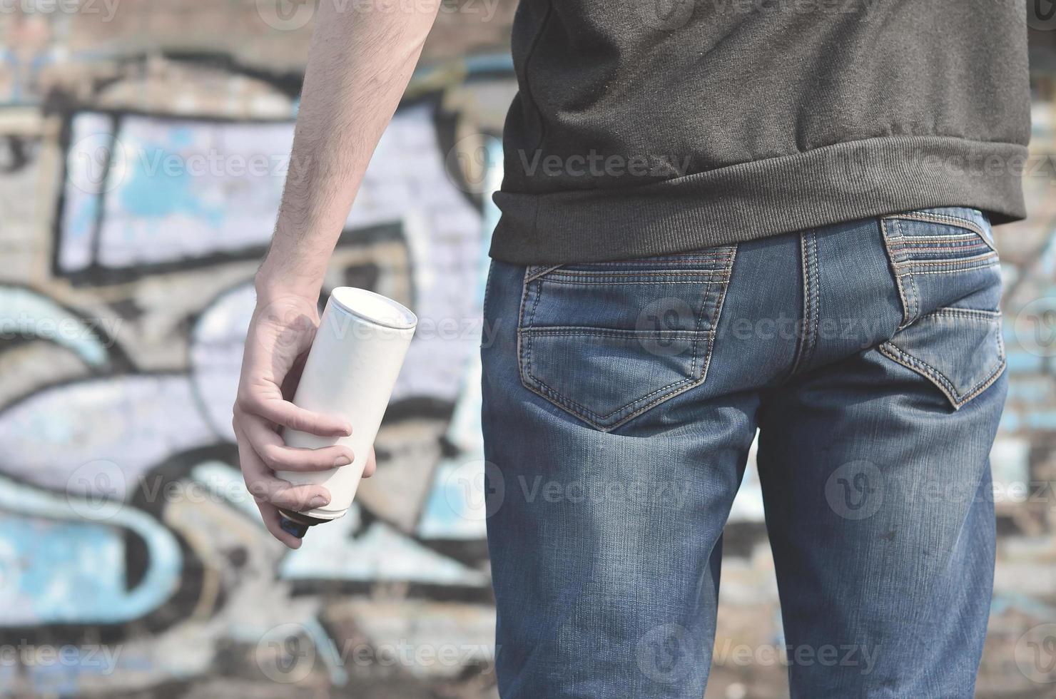 Graffiti artist with a spray can in his hand. Back view photo