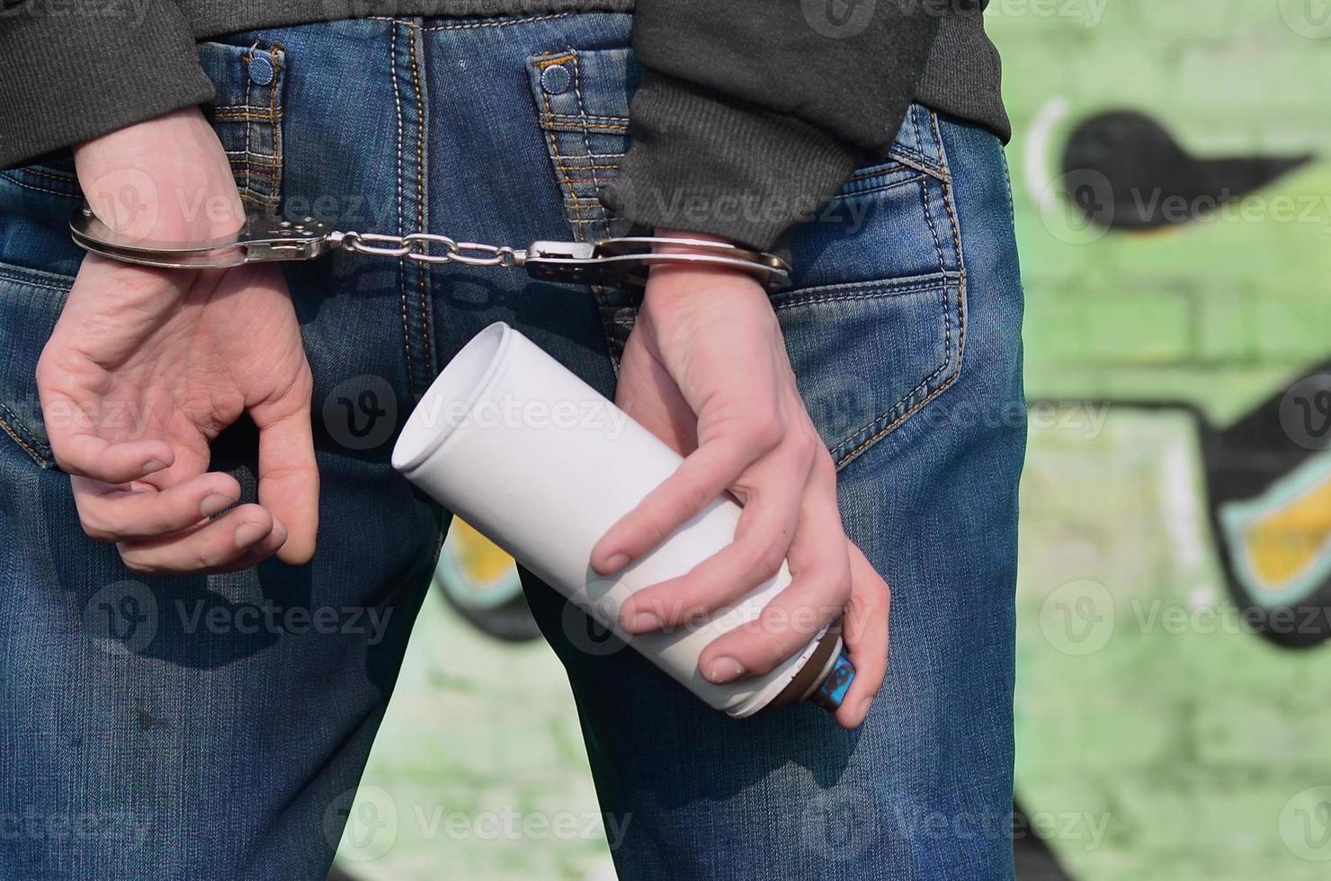 Young hoodlum caught by the police and shackled in handcuffs wit photo