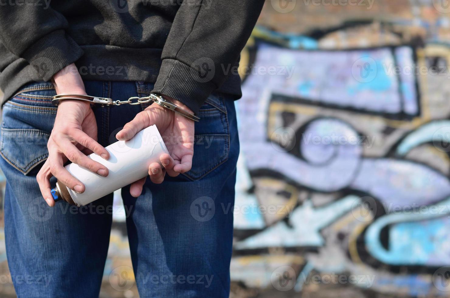 Young hoodlum caught by the police and shackled in handcuffs wit photo