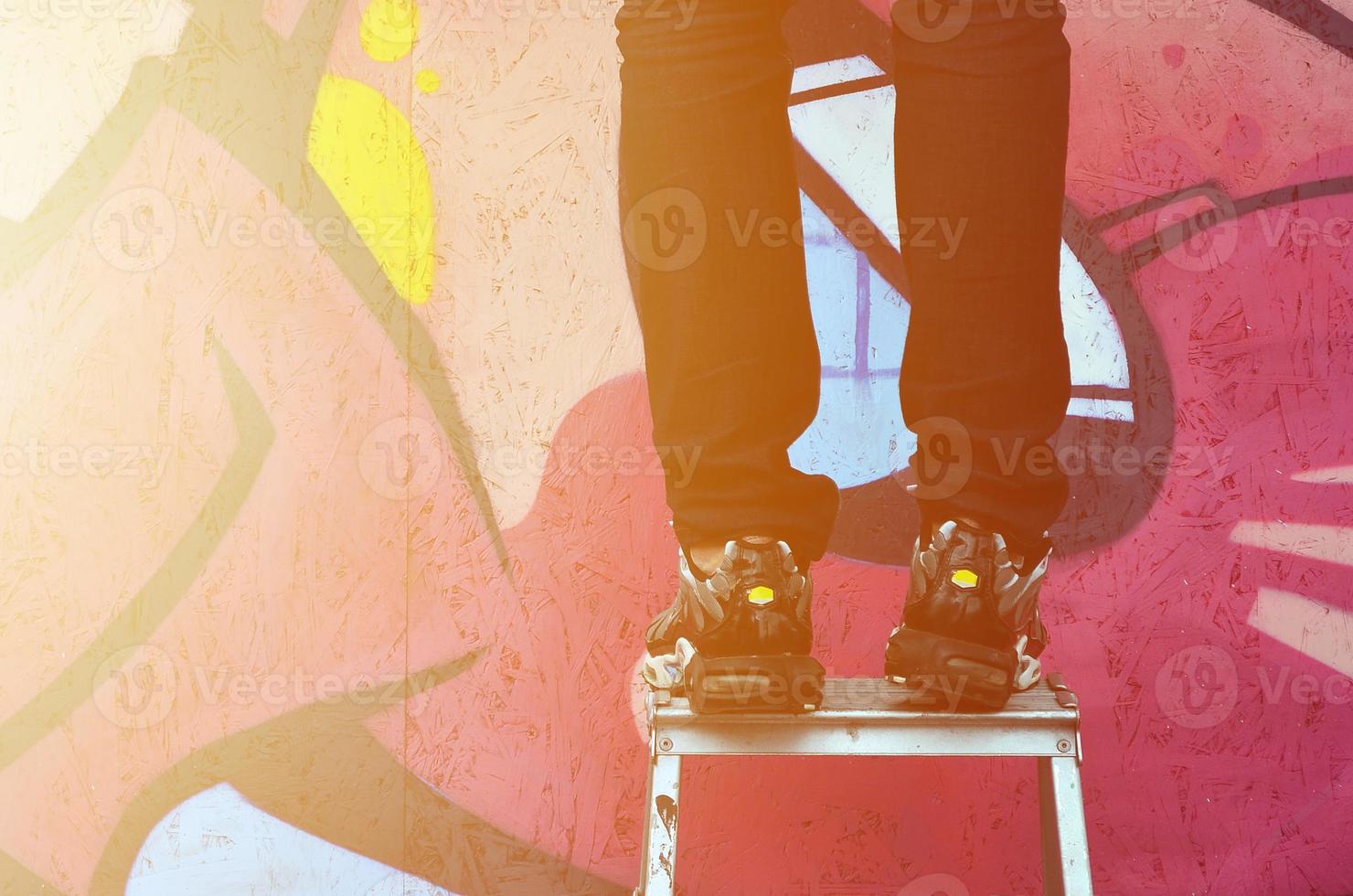 A young graffiti artist paints a new graffiti on the wall. Photo of the process of drawing a graffiti on a wall close-up. The concept of street art and illegal vandalism