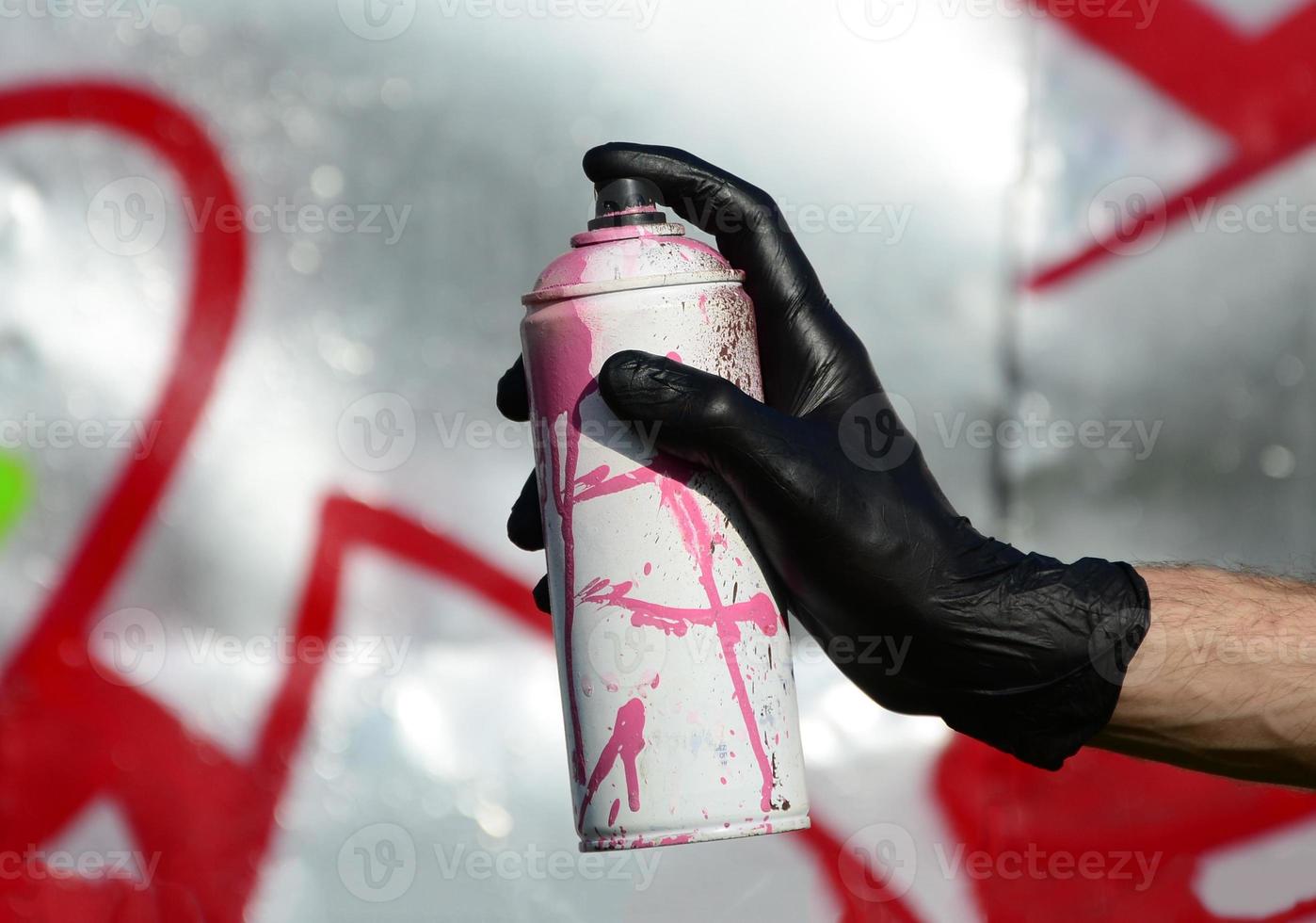 A hand with a spray can that draws a new graffiti on the wall. Photo of the process of drawing a graffiti on a metal wall. The concept of street art and illegal vandalism