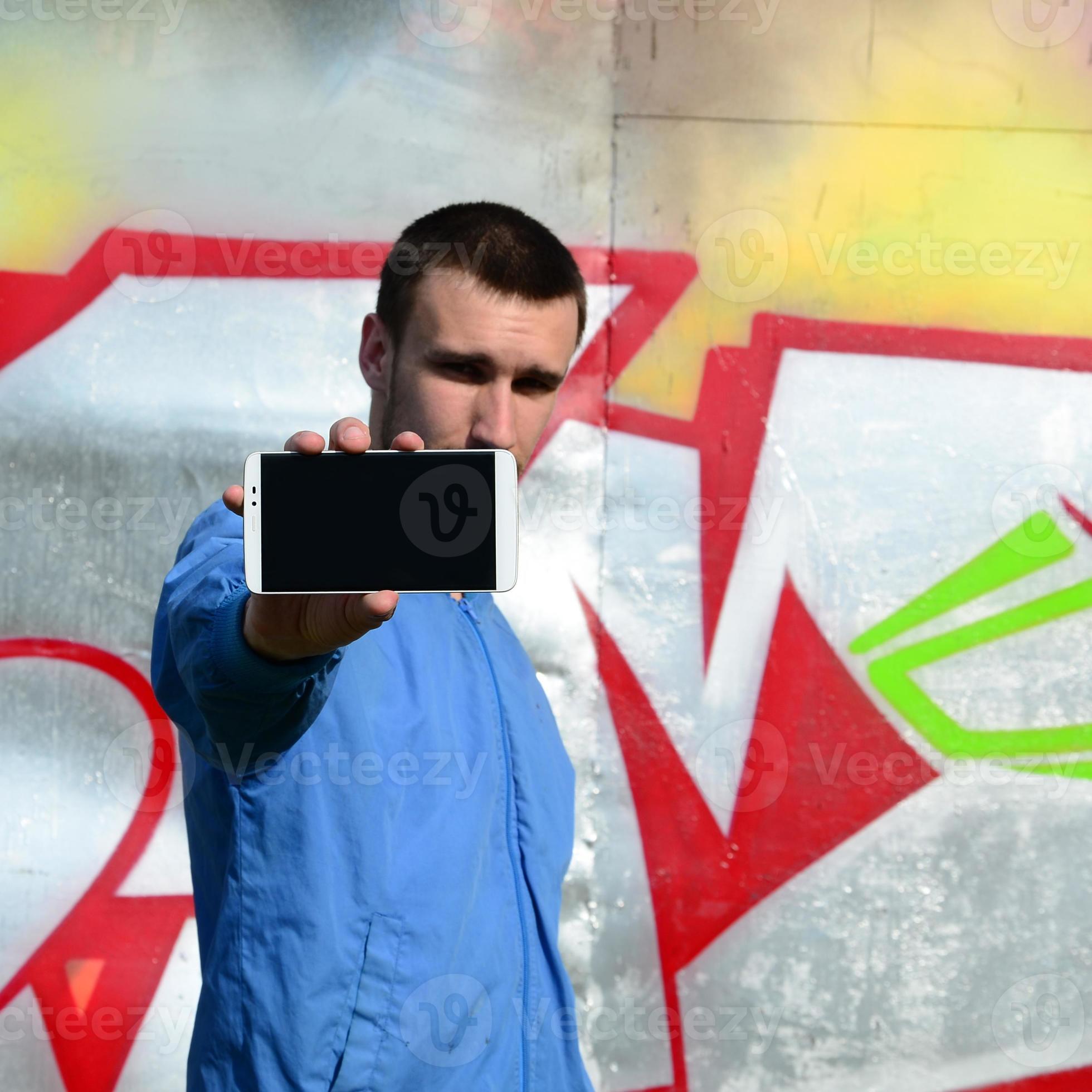 The graffiti artist demonstrates a smartphone with an empty black