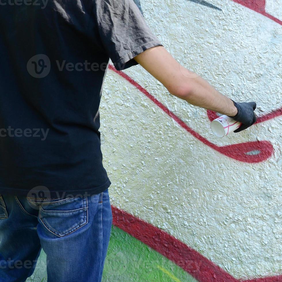 un joven gamberro pinta graffiti en una pared de hormigón. concepto de vandalismo ilegal. arte callejero foto