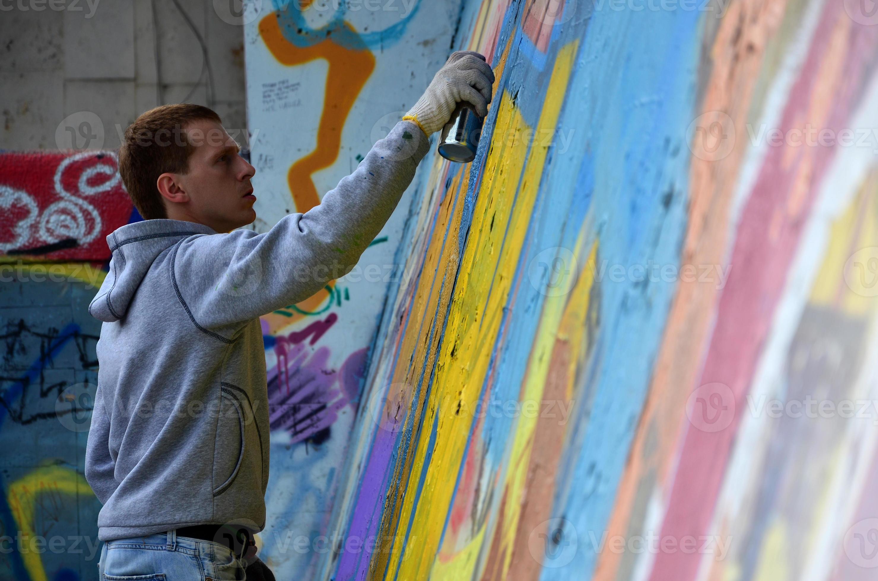 A young redhaired graffiti artist paints a new graffiti on the wall
