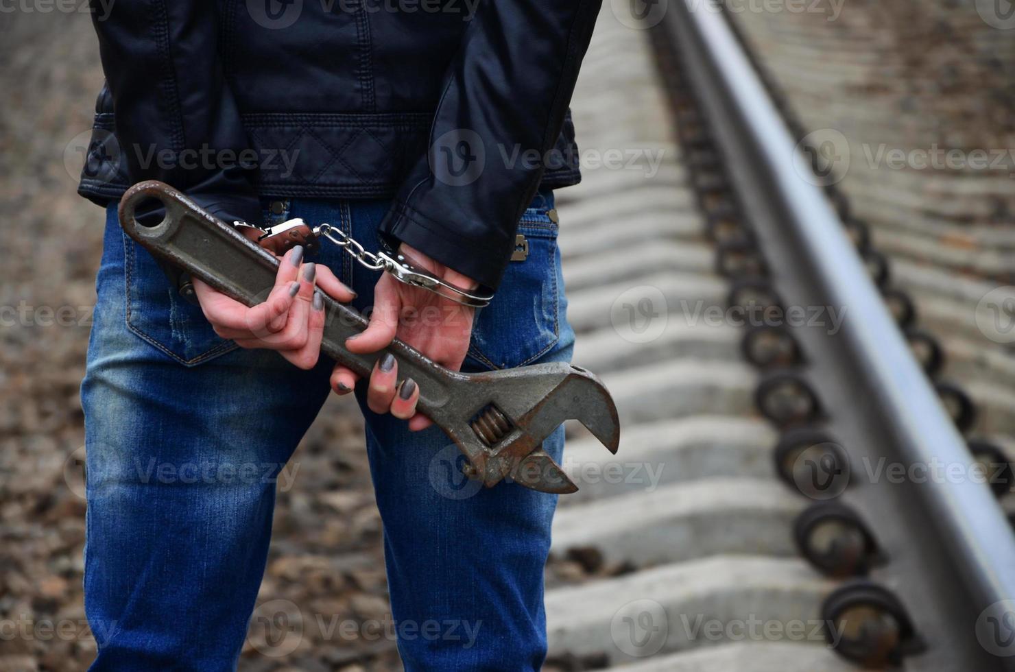 la chica esposada con la llave ajustable en el ferrocarril foto