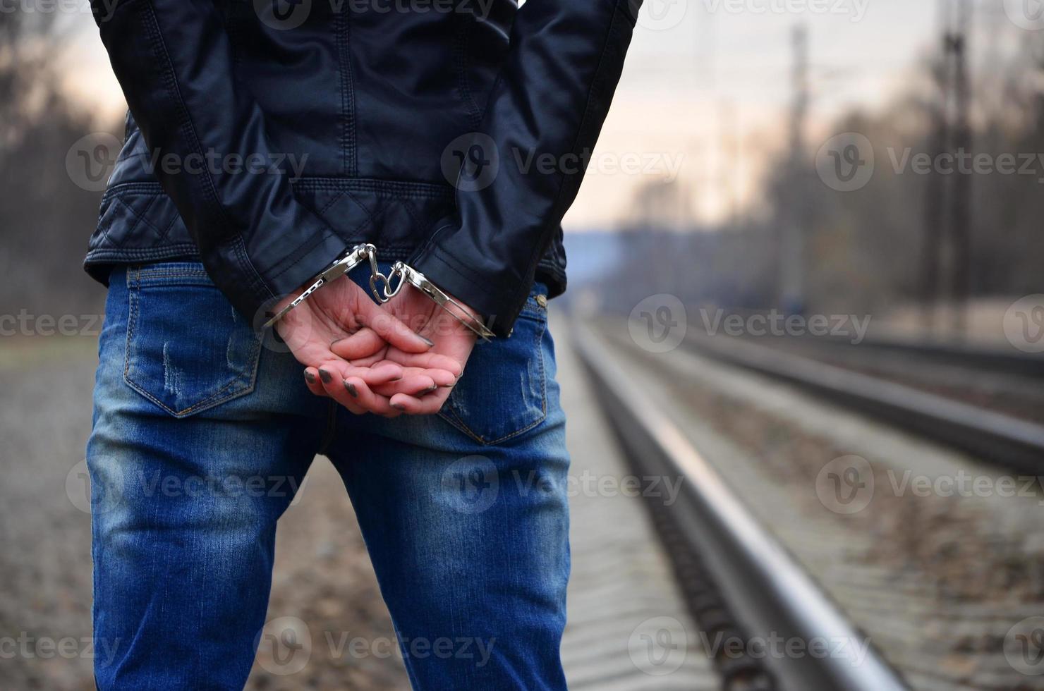 Girl in handcuffs on the background of a railway track photo