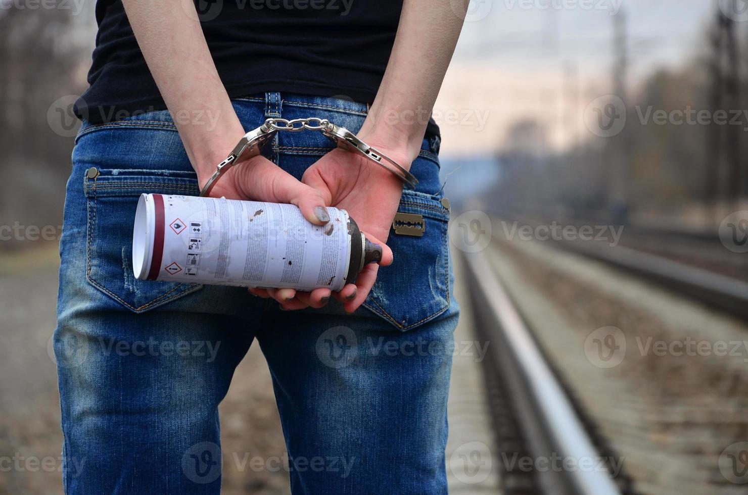 Girl in handcuffs with spraycan on the background of a railway t photo