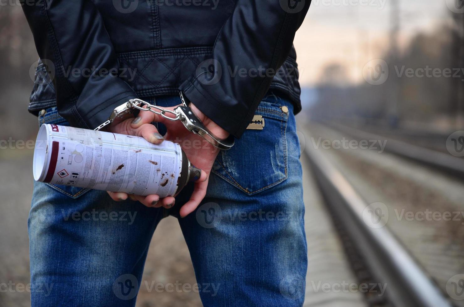 Girl in handcuffs with spraycan on the background of a railway t photo