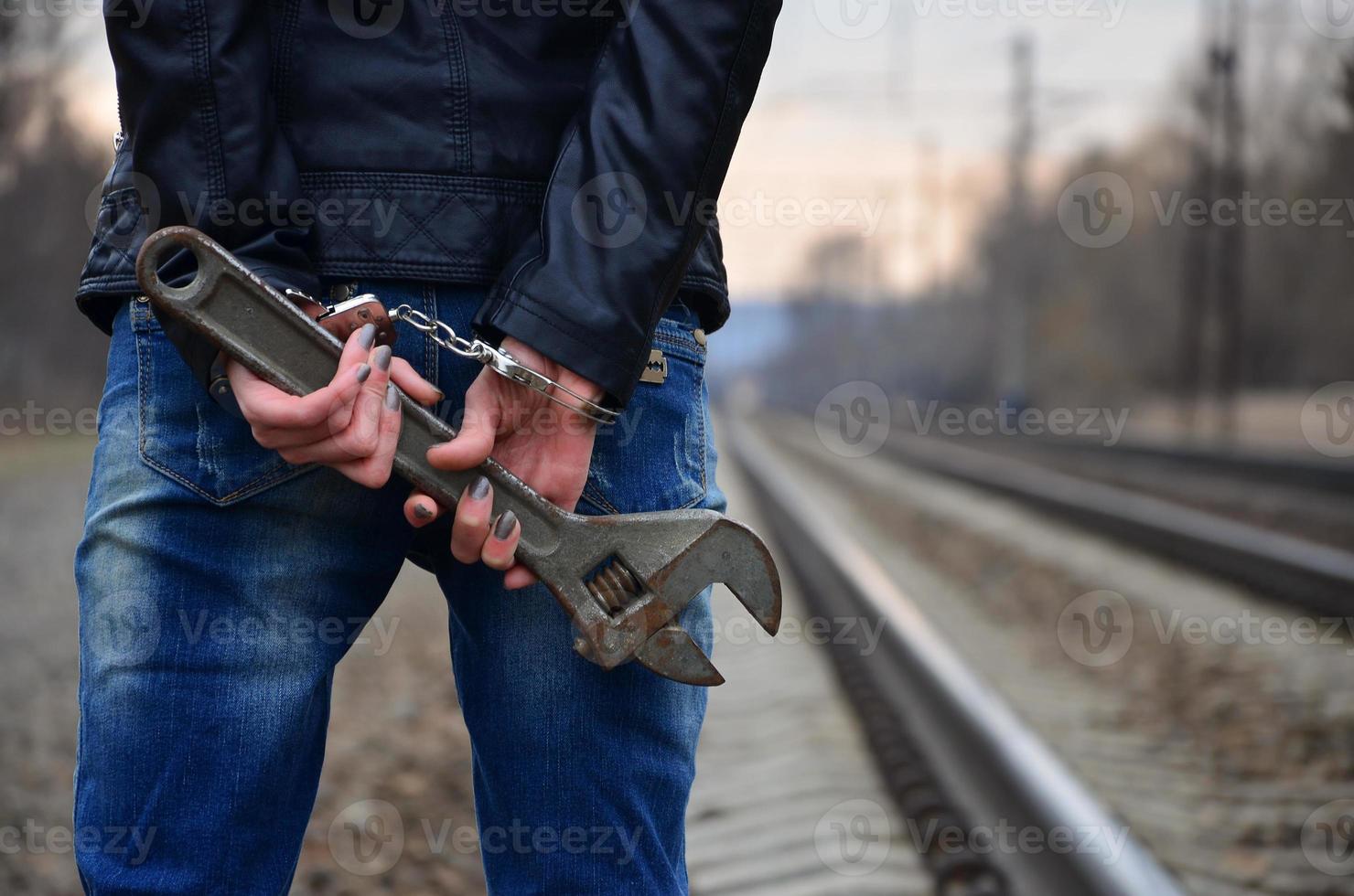 The girl in handcuffs with the adjustable wrench on the railway photo