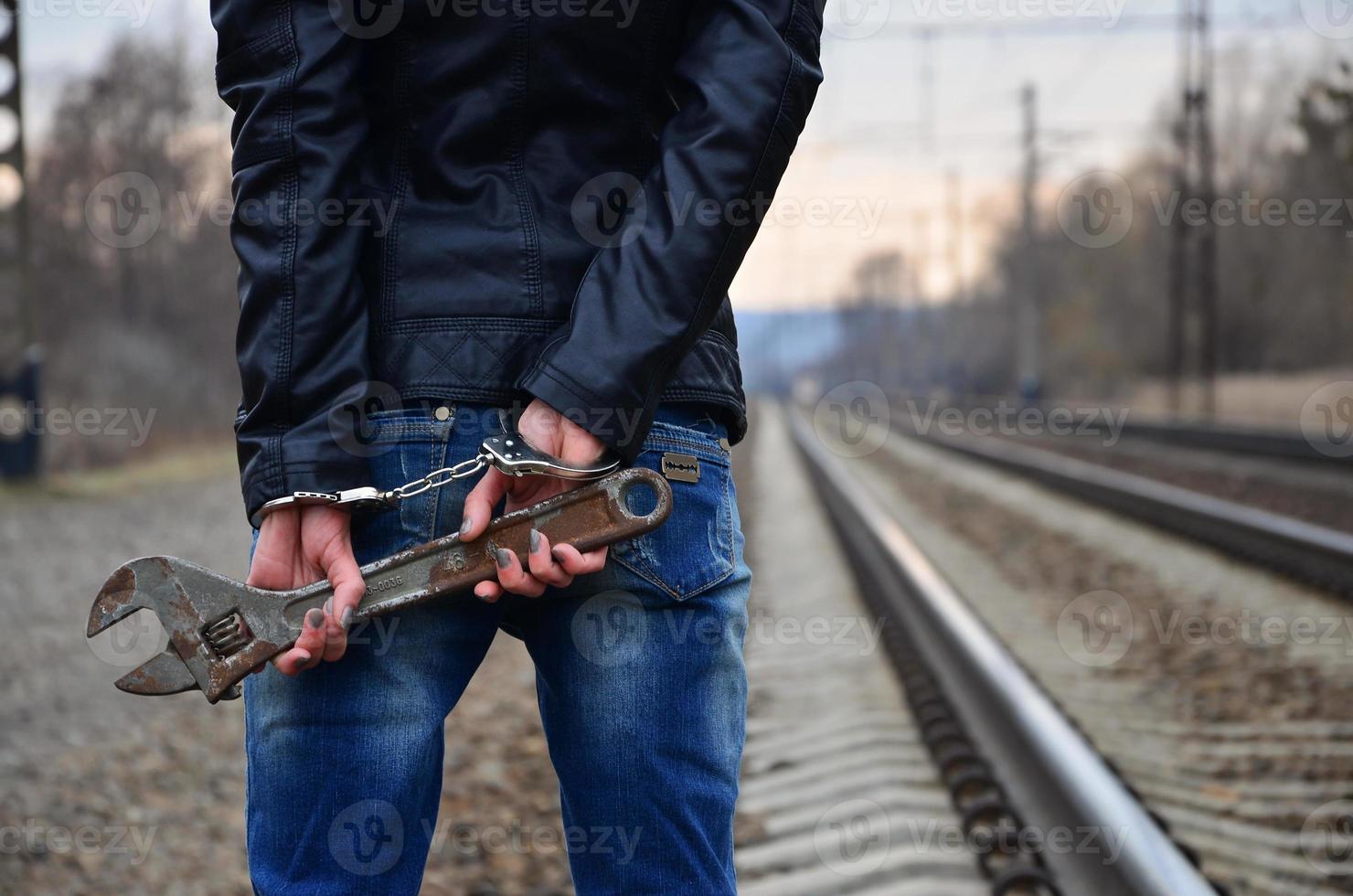 la chica esposada con la llave ajustable en el ferrocarril foto