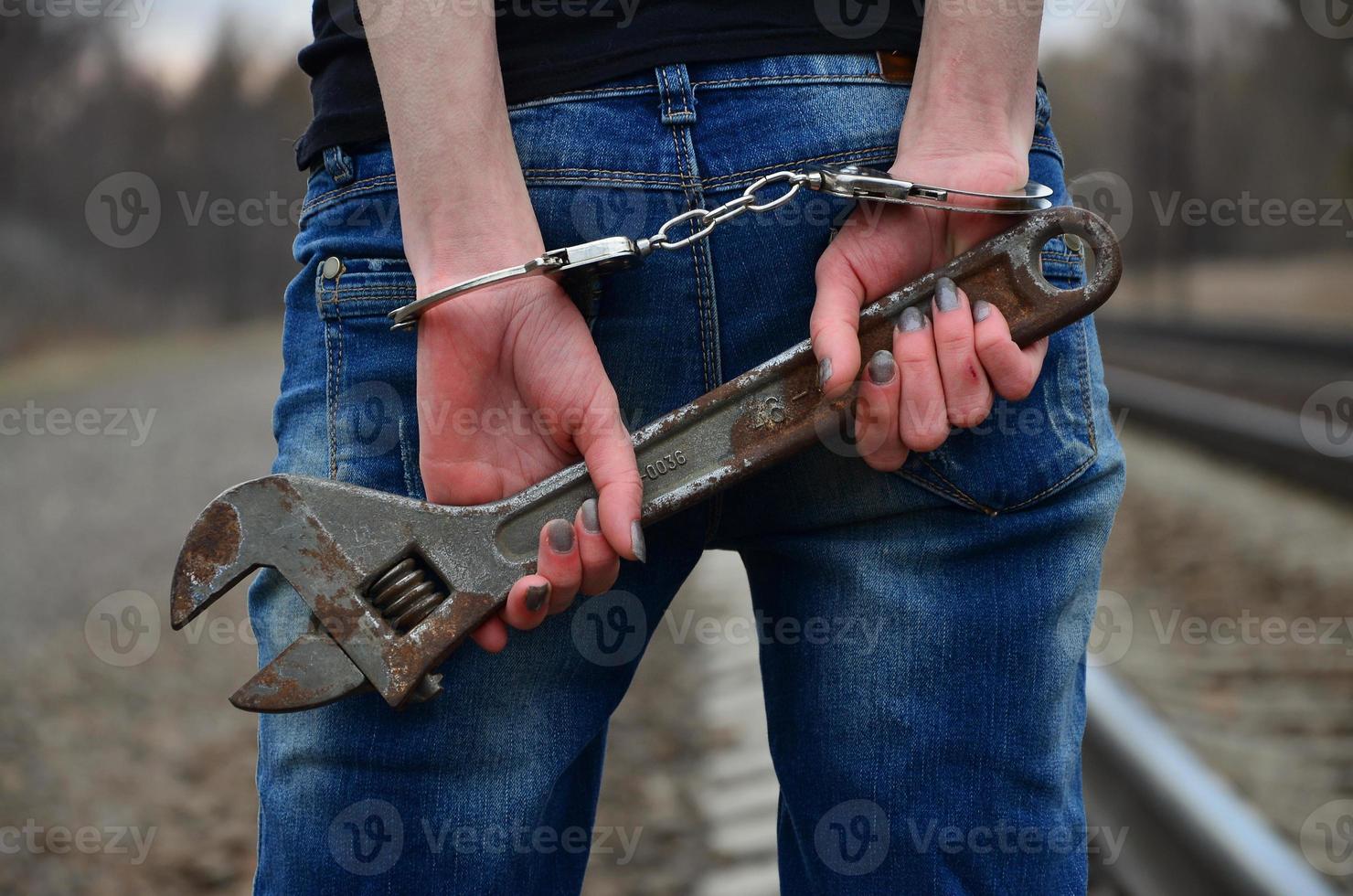 The girl in handcuffs with the adjustable wrench on the railway photo