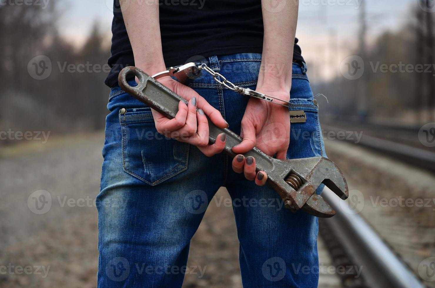 la chica esposada con la llave ajustable en el ferrocarril foto