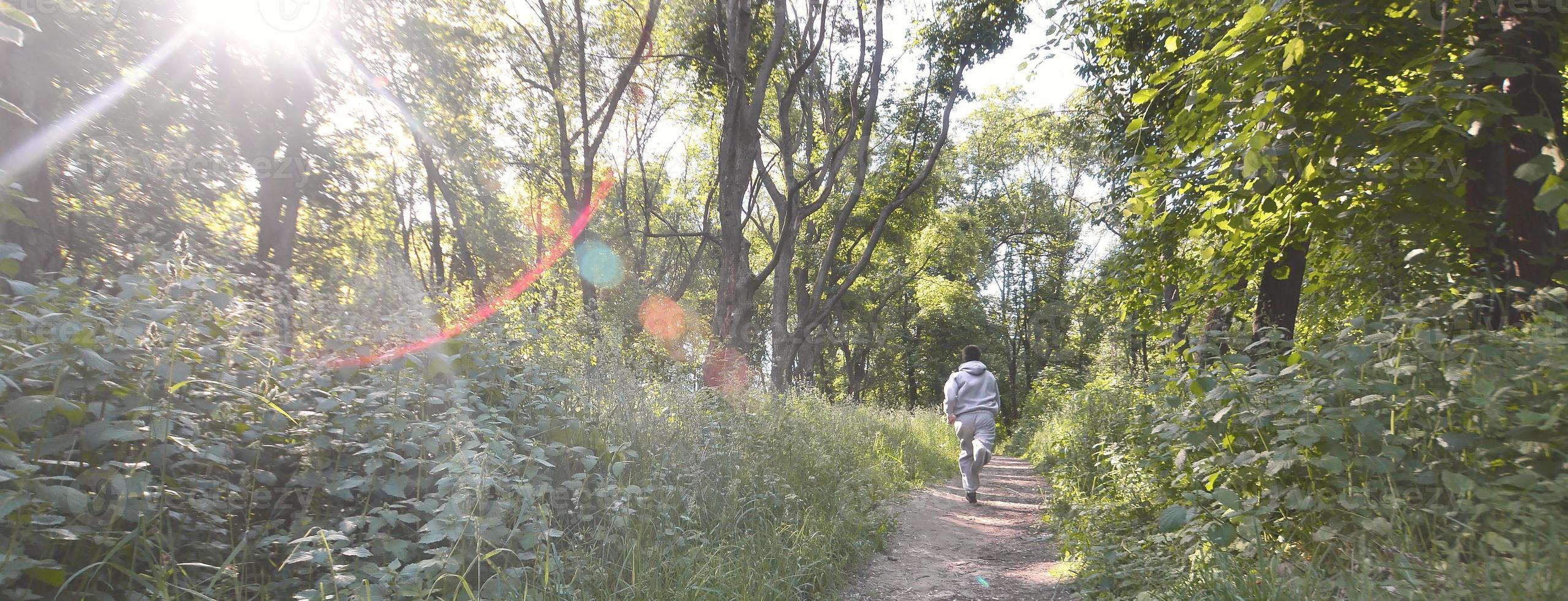 un joven con un traje deportivo gris corre por el camino entre los foto