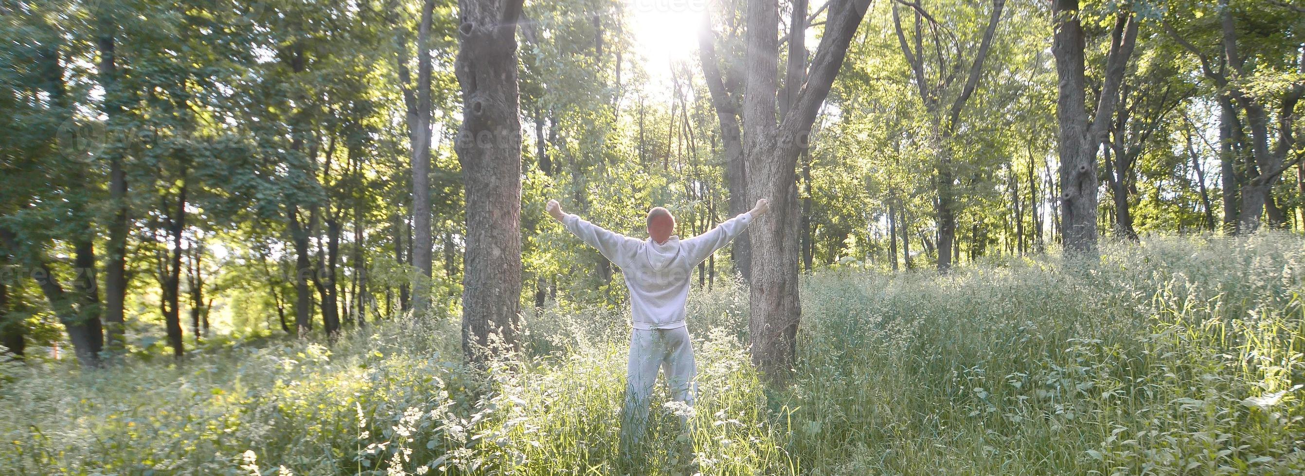 A young guy in a gray sports suit rejoices in the rising of the photo