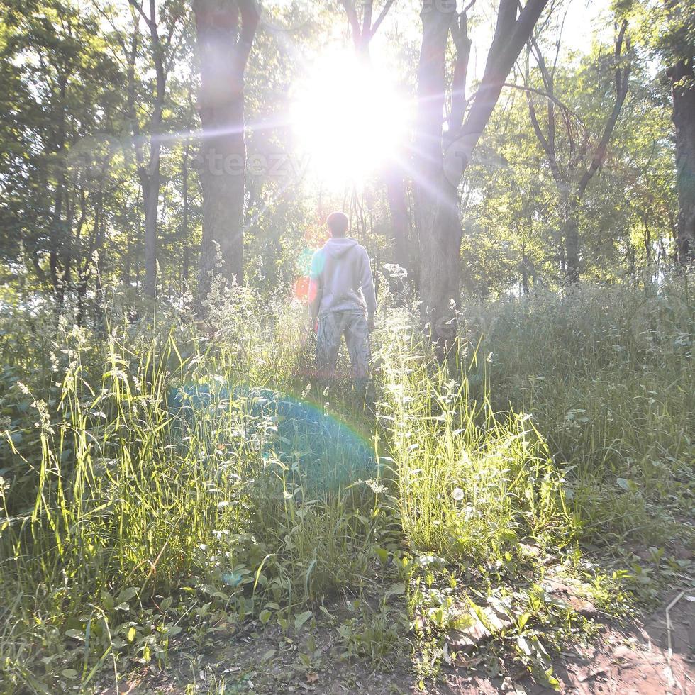 un joven con un traje deportivo gris se para frente al sol entre foto