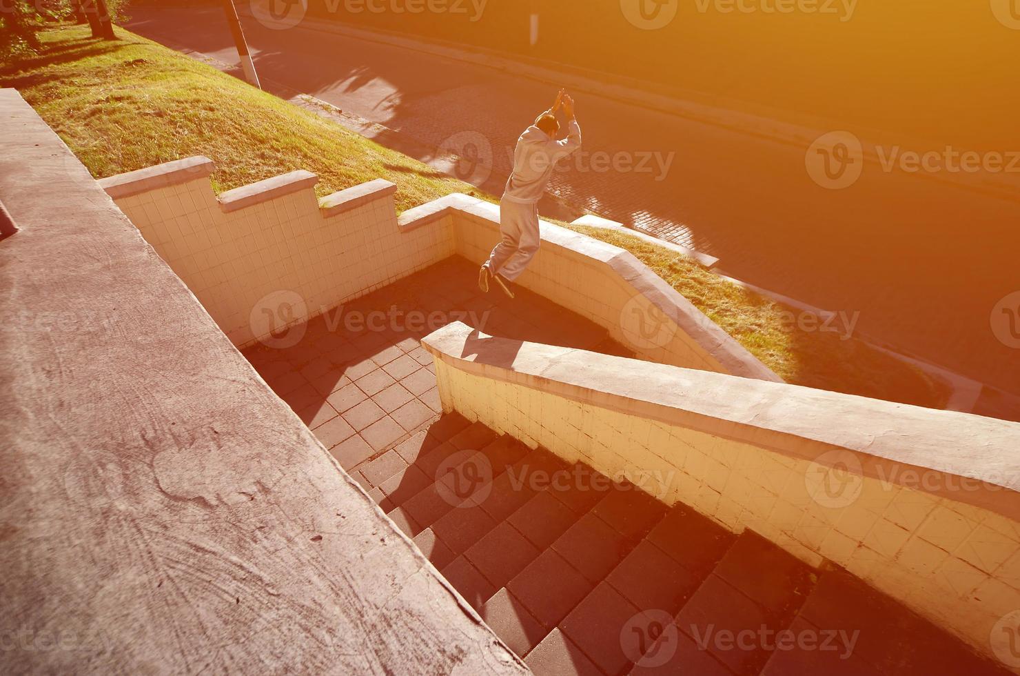 A young guy performs a jump through the space between the concrete parapets. The athlete practices parkour, training in street conditions. The concept of sports subcultures among youth photo