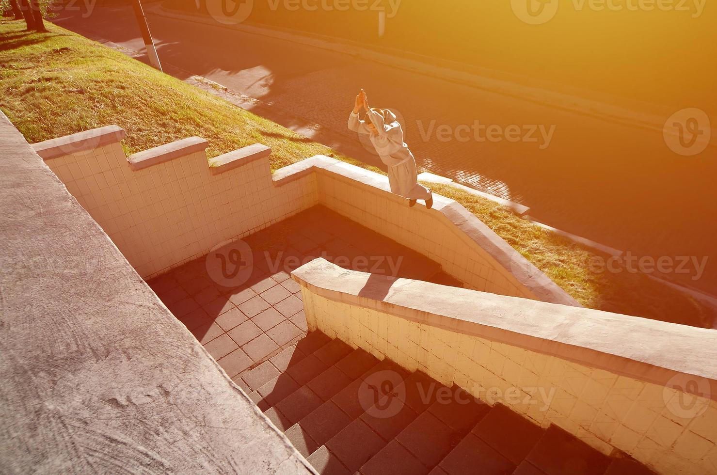 un chico joven realiza un salto a través del espacio entre los parapetos de hormigón. el atleta practica parkour, entrenando en condiciones de calle. el concepto de subculturas deportivas entre los jóvenes foto