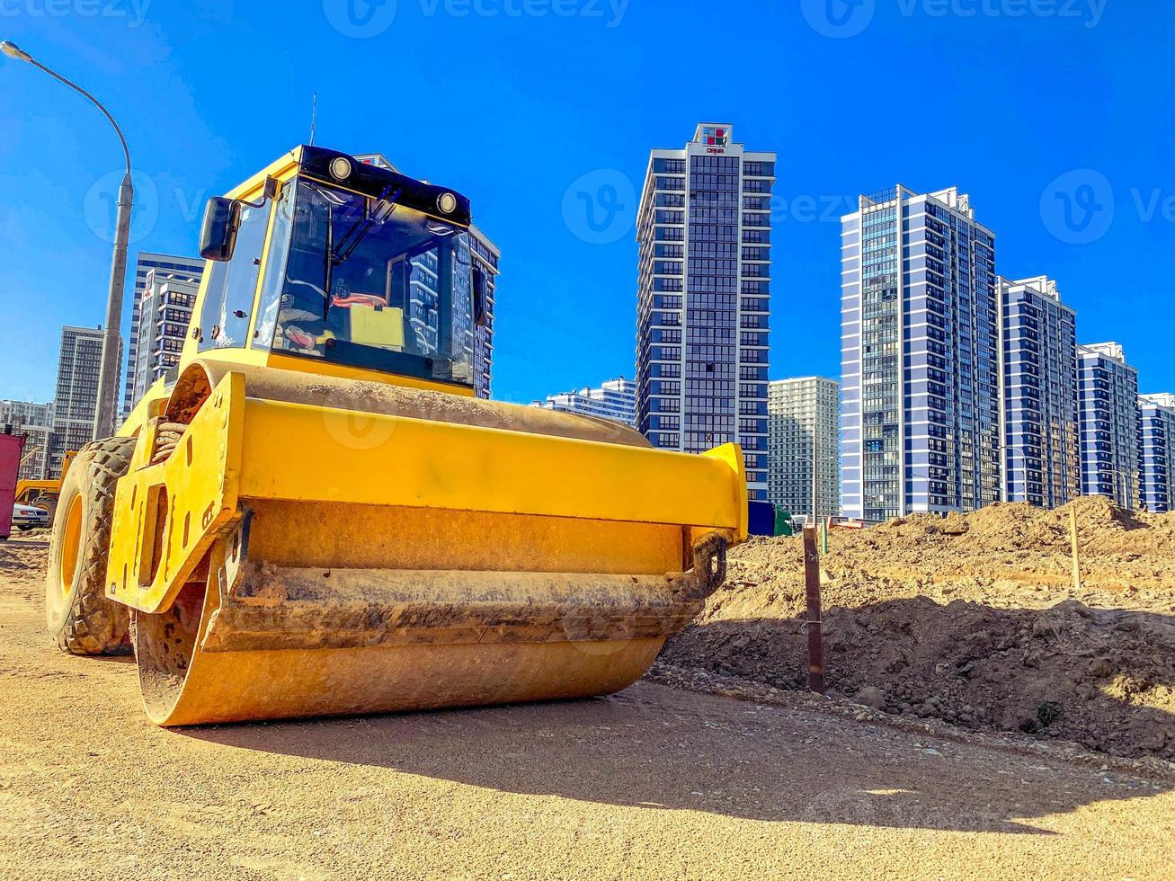 construction of a new microdistrict in the city center. high, multi-storey buildings made of concrete and glass. next to the house yellow excavator for construction photo