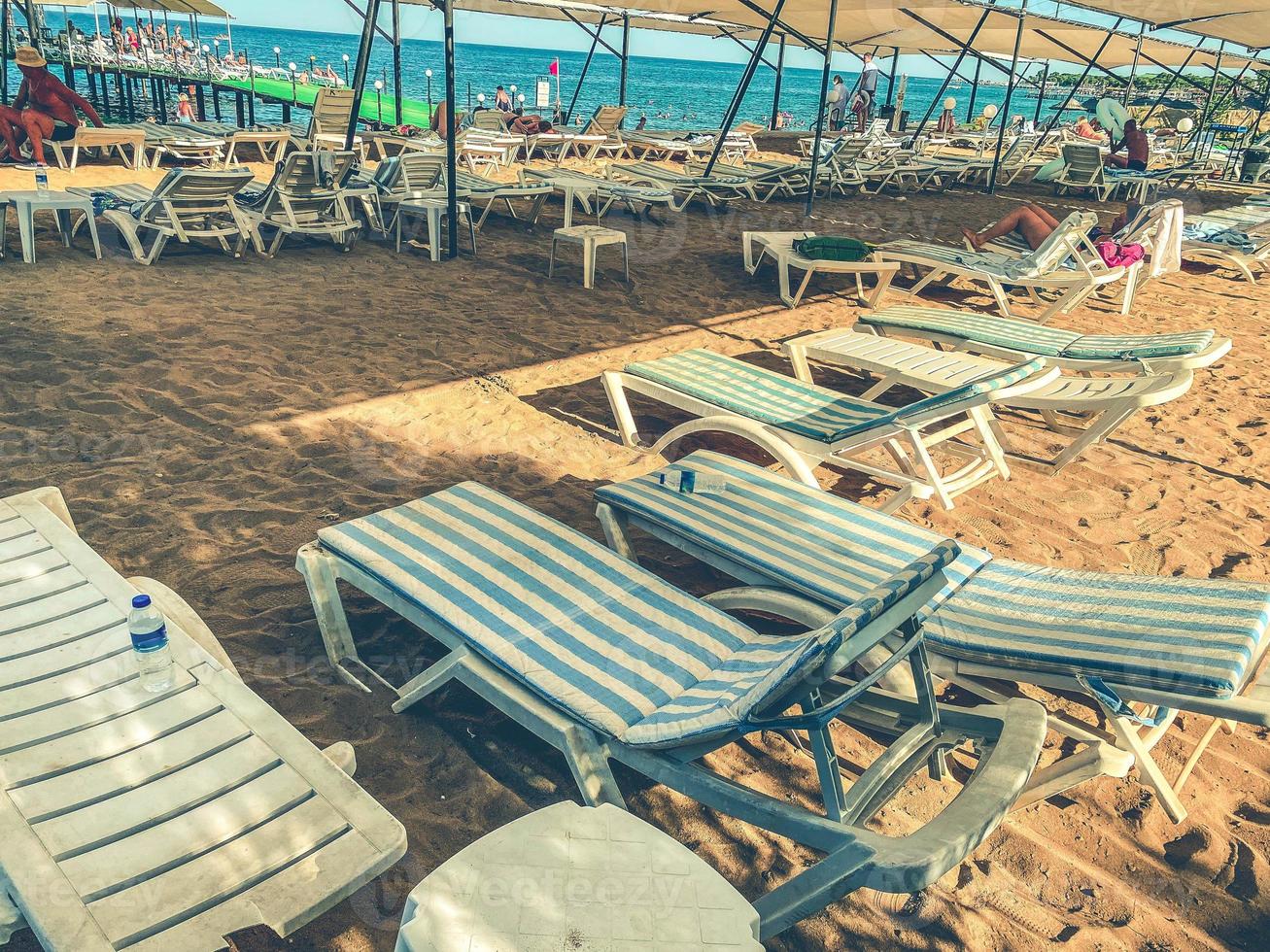 tumbonas chaise longue en la playa tropical vacía y el mar turquesa - panorama de vacaciones de ensueño en un destino exclusivo con arena blanca en un hermoso día soleado. foto