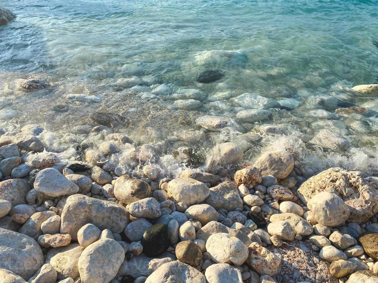 costa del mar en la orilla, entre la arena, yacen piedras lavadas por el agua. arena fina para pasear por la playa. belleza del mundo marino, vacaciones en países cálidos foto