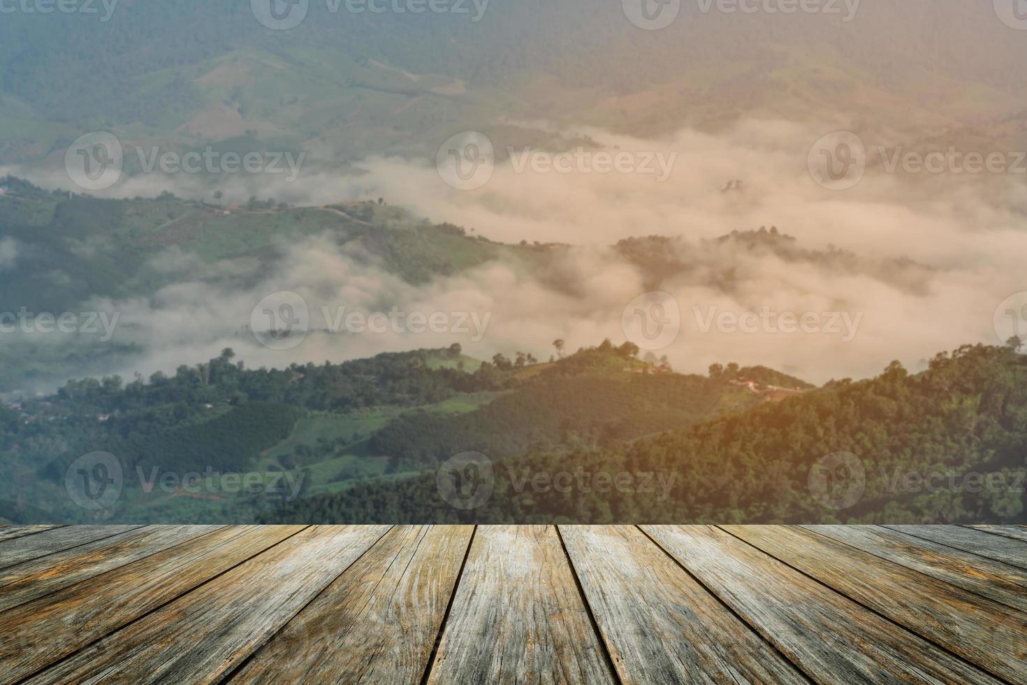 Wood floor foreground on sunrise landscape with mountain and fog mist winter weather sun lighting under vibrant colorful morning sky in mountains. Nature mountain sky and clouds sunset concept. photo