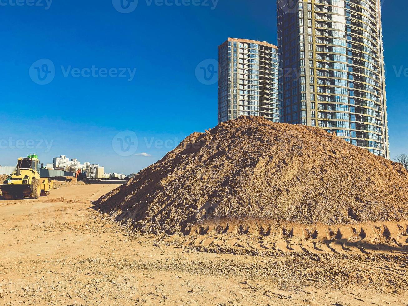 sand at a construction site in a new neighborhood. large, sandy heaps against the backdrop of houses erected from blocks and glass. high-rise buildings for residents of the city photo