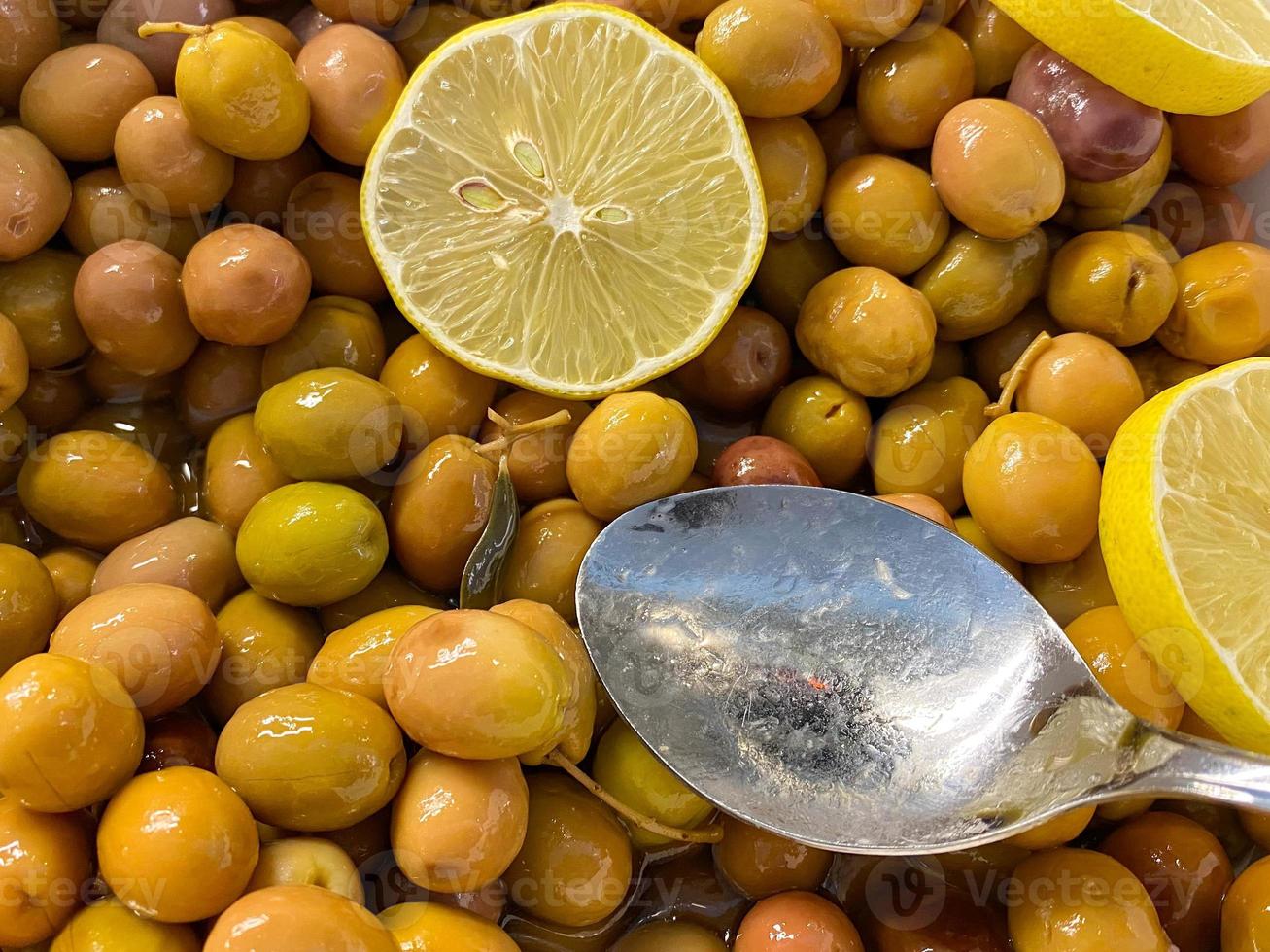 Yellow green tasty olives with lemon in a plate. Background, texture photo