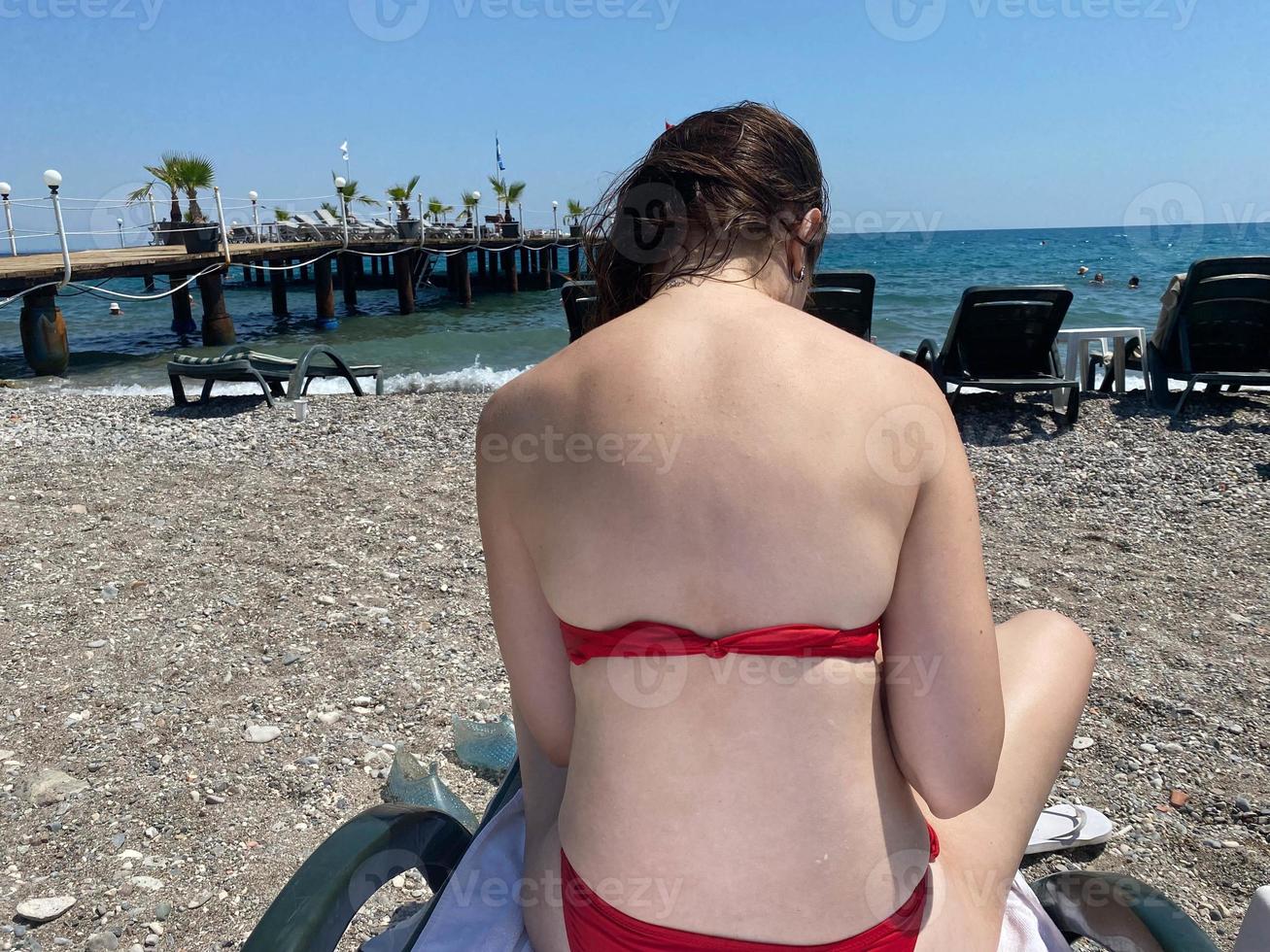 Woman drinking from thermos and sitting on camping chairs on the beach photo