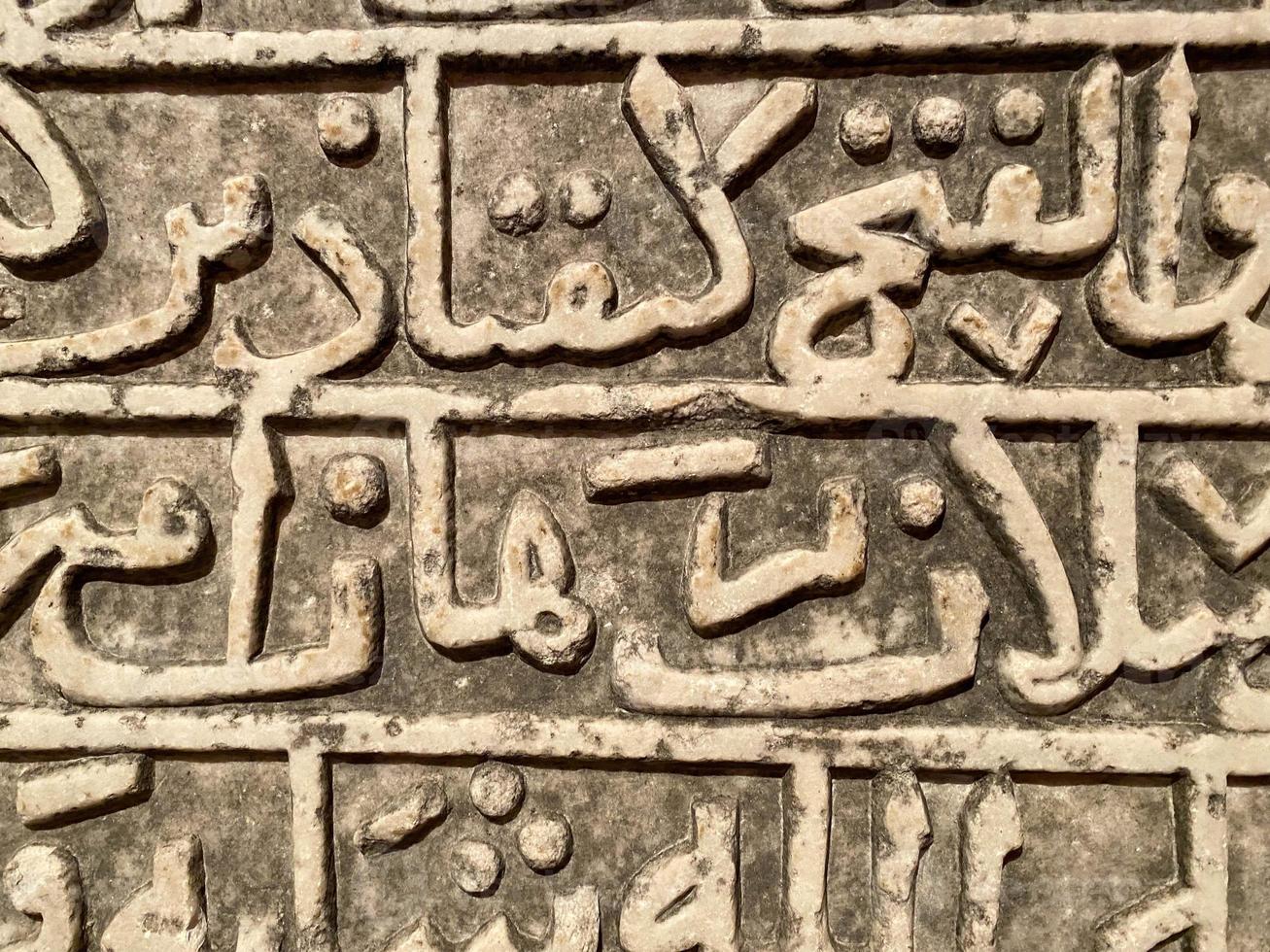 Stone tablet with ancient arabic inscriptions on the wall photo