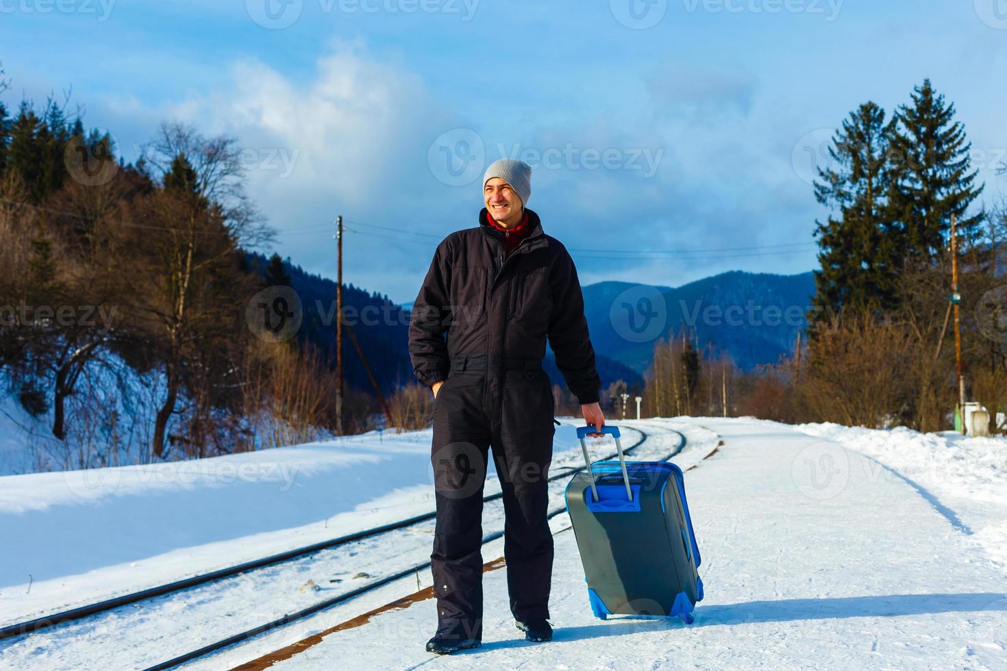 man in winter clothes standing on the platform of a train station photo