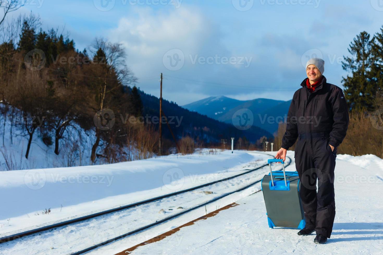 man in winter clothes standing on the platform of a train station photo