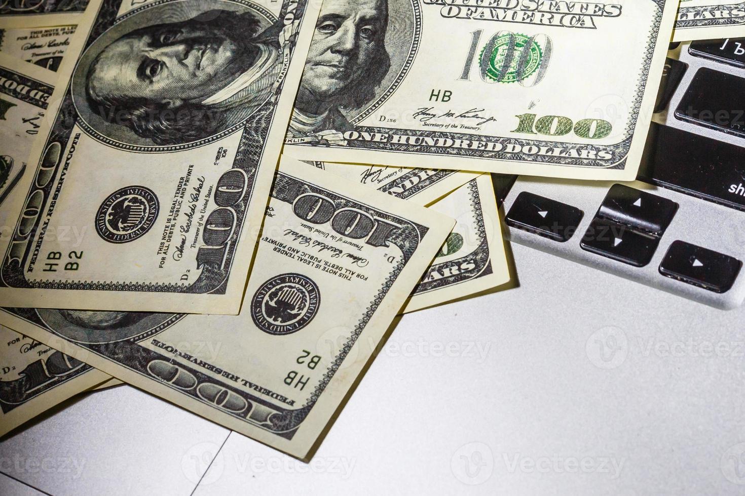 Closeup view of one hundred dollar banknotes lying on the laptop keyboard. photo
