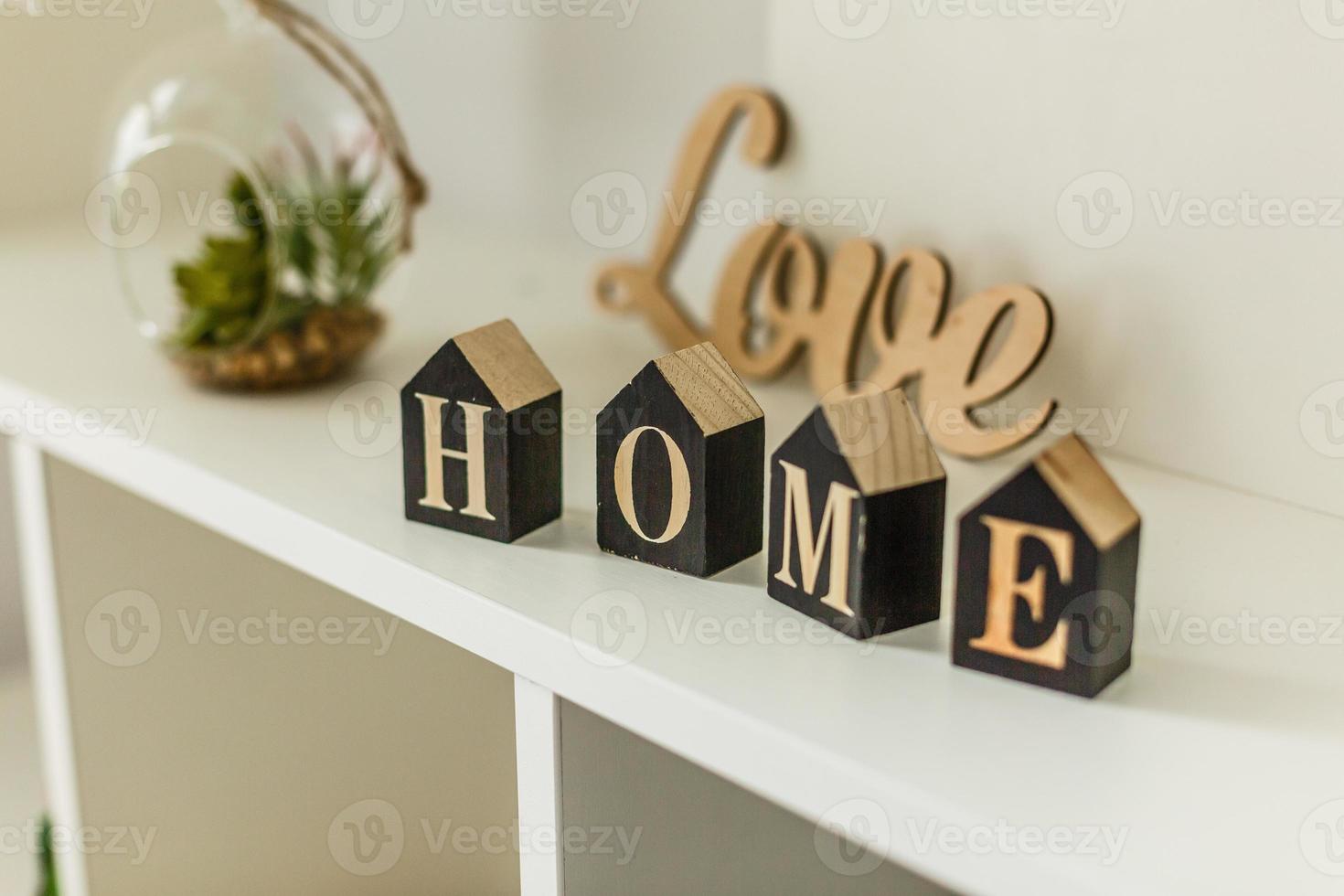 Word home on white wooden background with copy space. Home word concept. Home word written on black wooden houses. photo